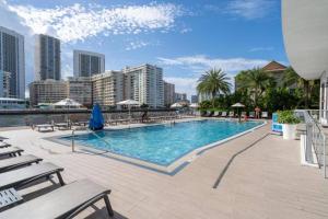 a large swimming pool with chairs and a city at Scenic Miami Beach Oasis - Full Kitchen -08A in Hallandale Beach