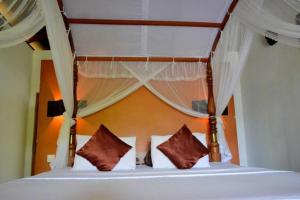 1 cama con 2 almohadas y dosel en Landa Holiday House, en Belihuloya