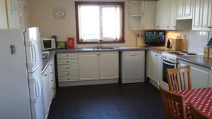 a kitchen with white appliances and a table and a window at Druim Mor in Stornoway