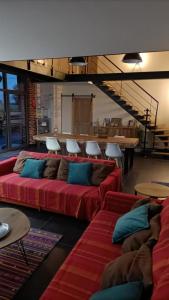 un soggiorno con divani rossi, tavoli e scale di La grange des deux pays a Nieppe