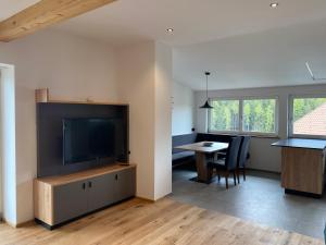 uma sala de estar com uma televisão de ecrã plano e uma mesa em Alpenglow Apartments em Collalbo