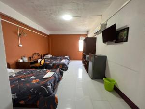 a hotel room with three beds and a desk at GG Sweet Home in Mae Sot