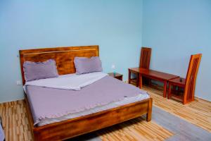 a bedroom with a wooden bed and a desk at IREBERO DREAM HOME in Kayonza