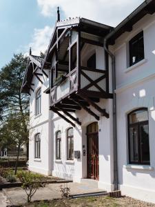 a white house with a balcony on it at HORAMI Villa - OKYU Apartment in Malchow