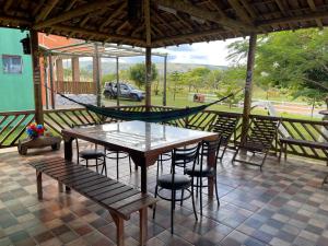 a table and chairs on a patio with a hammock at Sítio Lourenço Marques Serra do Cipó MG in Serra do Cipo