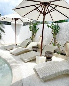 a group of chairs and umbrellas next to a pool at Kemari Studio in Canggu
