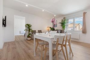 a white dining room with a white table and chairs at Flamingo Center Clemenceau in Béziers