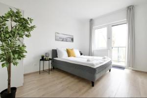 a white bedroom with a bed and a potted plant at Family Apartments by Hi5 - Zamardi in Zamárdi