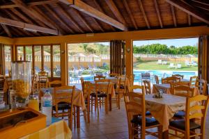 um restaurante com mesas e cadeiras com vista para uma piscina em Bardis Hotel em Arillas