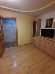een woonkamer met een televisie en een deur bij Кандавас 9 in Daugavpils