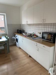 a kitchen with white cabinets and a sink and a microwave at WG Zimmer 108 in Holzminden