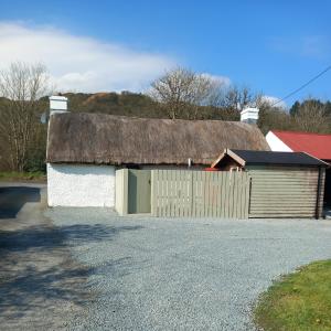a barn with a thatched roof and a garage at Eddie's Roadside Thatched Cottage 