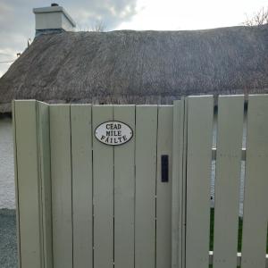 a white fence with a sticker on top of it at Eddie's Roadside Thatched Cottage 