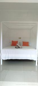 a white bed with two red pillows on it at Sekumpul BnB in Singaraja