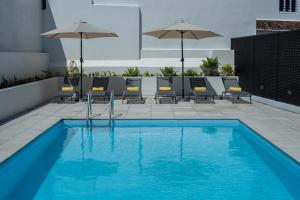 a swimming pool with chairs and umbrellas on a building at Olive Boutique Guesthouse in Vila Franca do Campo