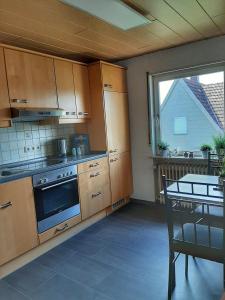 a kitchen with a stove and a table and a window at Hillis Ferienwohnung Saarland in Sankt Ingbert