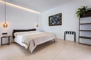 a white bedroom with a bed and a painting on the wall at Mana EcoRetreat in Las Breñas
