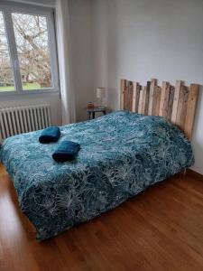 - une chambre avec un lit doté d'une couverture bleue et d'une fenêtre dans l'établissement Maison chaleureuse, gîte pour famille, amis, ouvriers..., à Château-Gontier