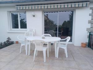 - une table et des chaises blanches sur la terrasse dans l'établissement Maison chaleureuse, gîte pour famille, amis, ouvriers..., à Château-Gontier
