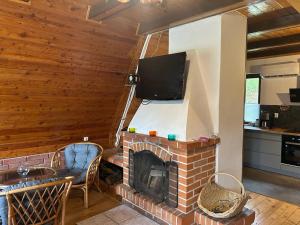 a living room with a brick fireplace with a flat screen tv at Dom Nad Jeziorem Raduńskim in Borucino