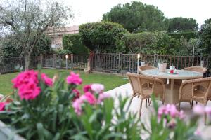 バルドリーノにあるCisano Holiday Apartmentのピンクの花が咲く庭園のテーブルと椅子