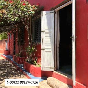 una puerta abierta a un edificio rojo con plantas fuera en IL PEVERO, en Flecheiras