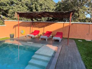 卡普斯基靈的住宿－Villa Paradis magnifique vue mer，一个带红色椅子的游泳池和一个凉亭
