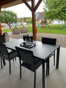 una mesa negra y sillas con un parque infantil en el fondo en Gîte L'Ecrin du Ried "COSY", en Artolsheim