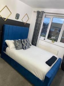 un letto blu in una stanza con finestra di Stunning 3-bedroom Great Sankey Home a Great Sankey