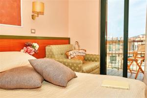1 dormitorio con 1 cama, 1 silla y balcón en Hotel La Pergola, en Santa Maria di Castellabate