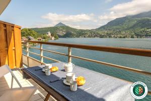 a table on a balcony with a view of the water at Les Libellules accès direct au lac, 7 apts du studio au 4 ch, LLA Selections by LocationlacAnnecy in Duingt