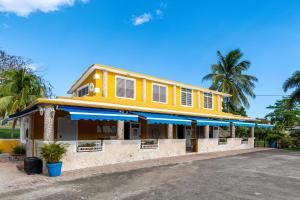 un edificio amarillo con sombrillas azules en una calle en Casamares Private Room Coral with Pool and Jacuzzi 5 min to Boqueron and Beaches, en Cabo Rojo