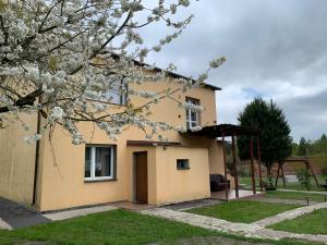 une maison avec un arbre à fleurs devant elle dans l'établissement Noclegi Little Sheep, à Chojna