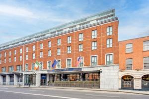 een groot rood bakstenen gebouw met vlaggen erop bij The Trinity City Hotel in Dublin