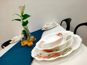 a table with two plates and a vase with a flower at SALAM Homestay D'Gerik in Gerik