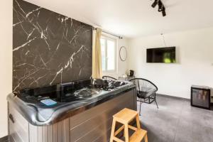 bañera en una habitación con pared de mármol negro en LE CHILL Suite & SPA (Jacuzzi et Sauna privés), en Boissy-Saint-Léger