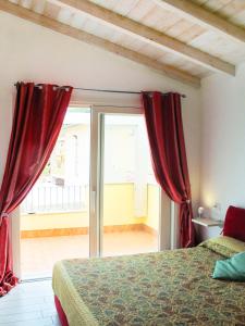 a bedroom with a bed and a window with red curtains at Affittimoderni Viddalba Terme in Lu Razzoni