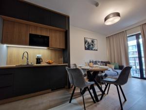 a kitchen and living room with a table and chairs at Apartamenty przy plaży Shellter in Rogowo