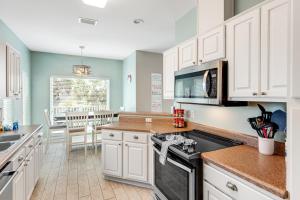 a kitchen with white cabinets and a stove top oven at Beachy Dreams in Pensacola Beach