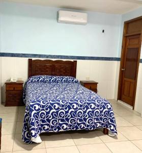 a bedroom with a bed with a blue and white comforter at Hotel San Fernando Ciudad Valles in Ciudad Valles