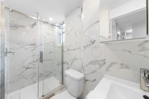 uma casa de banho branca com um chuveiro e um WC. em Stonewall Suites em Montreal