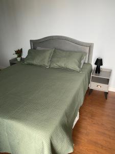 a bed with a green comforter and a night stand at Flat BOUTIQUE em frente ao metrô MOEMA in São Paulo