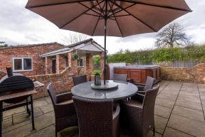 un tavolo con sedie e un ombrellone su un patio di The Gardens - Stunning Farmhouse a York