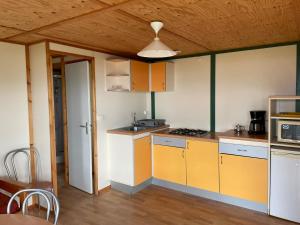 a kitchen with yellow and white cabinets and a wooden ceiling at La vallée in Belvédère
