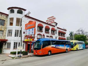 dos autobuses están estacionados frente a un edificio en Hotel San Fernando Ciudad Valles en Ciudad Valles
