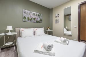 una camera da letto con un grande letto bianco con asciugamani di Hopstays - Gaia Cork House a Vila Nova de Gaia