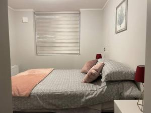 1 dormitorio con 1 cama con 2 almohadas y ventana en Departamento en Condominio Parque Francia en Osorno