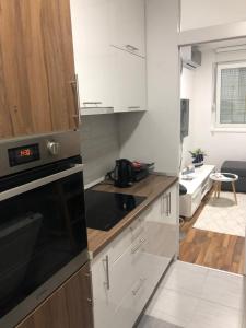 a kitchen with white cabinets and a black microwave at Apartment Mesic is 200 m away from the international airport in Sarajevo in Sarajevo