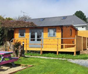 una casa amarilla con una valla y una mesa de picnic en The Stunning Log House, en Wexford