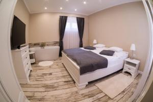 um quarto com uma cama, uma banheira, uma cama e uma televisão em Reforma Apartman em Szerencs